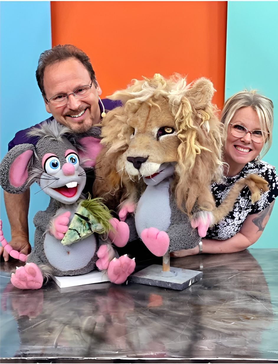 Smiling duo holding whimsical animal puppets